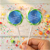 Personalised lollipops on white sticks, deep blue labels with gold cross, held in hand