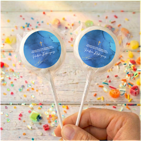 Two personalised lollipops with deep blue circular labels, gold cross, clear wrap