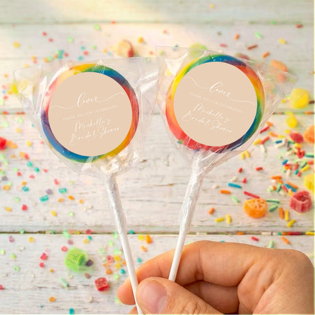 Personalized bridal shower lollipops with beige round labels and rainbow candy coating