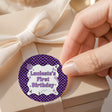 Purple checked round birthday label on white satin ribbon bow: Luciest's First Birthday
