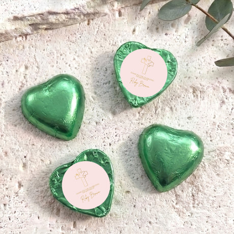 Green foil-covered chocolate hearts with cross design and personalized text on white inserts