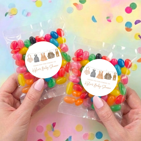 Two personalized jelly bean bags with round labels and multicolor candies, held by hands