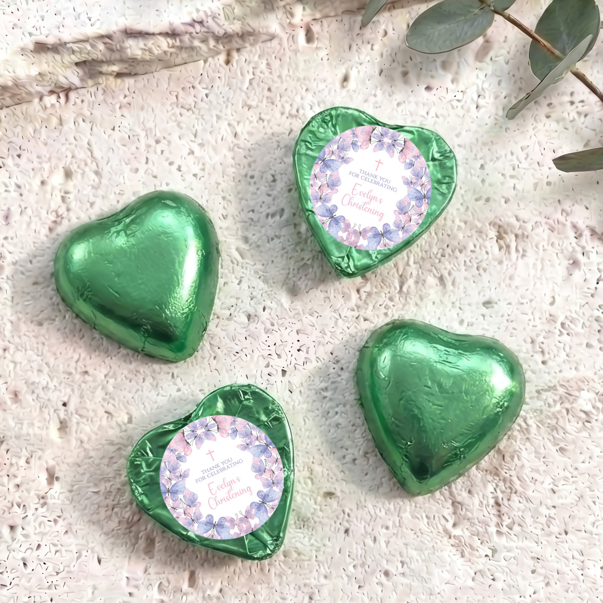 Green foil-covered heart chocolates with pastel floral baptism labels