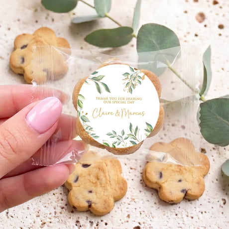 Hand holding bite-size chocolate chip cookie with round eucalyptus wedding label