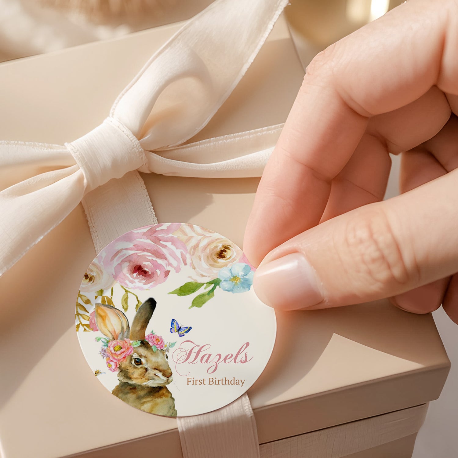Round printed first birthday label with floral bunny, 'Hazel's First Birthday'.