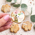 Hand holding personalised floral bunny first birthday choc chip cookie in clear wrapper