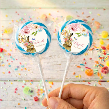 Personalised bunny floral lollipops with blue-bordered round labels, held in hand
