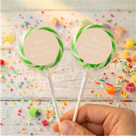 Personalised wedding lollipops with green swirl tops and beige thank-you labels