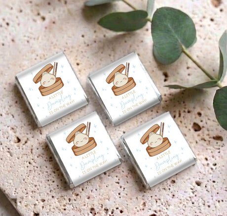 Four foil-wrapped personalised mini chocolates with baby dumpling labels on surface