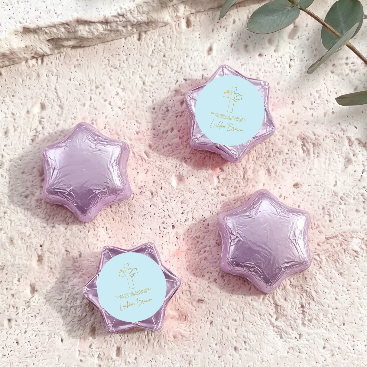 Foil-covered chocolate stars in purple with printed cross on white labels.
