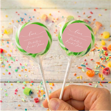 Bridal shower love lollipops: two wrapped candies with dusty pink round labels, green edges, sticks