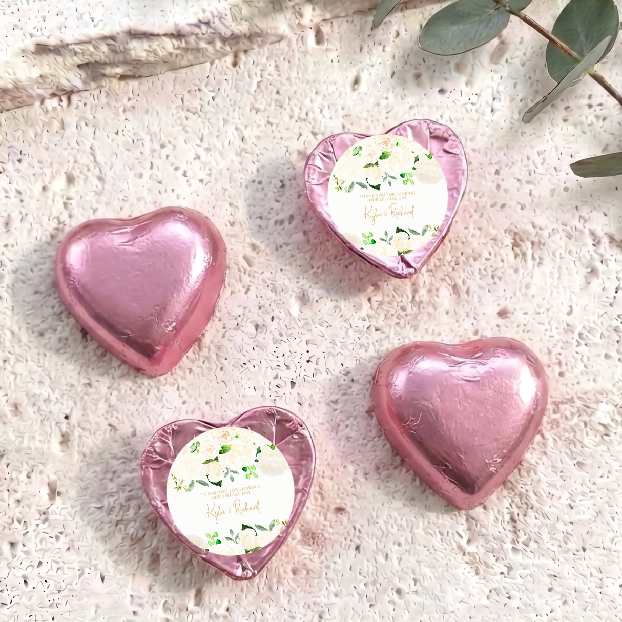 Pink foil-covered chocolate hearts with white floral personalised center label