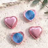 Pink foil-covered chocolate heart favors with gold cross and blue personalized label