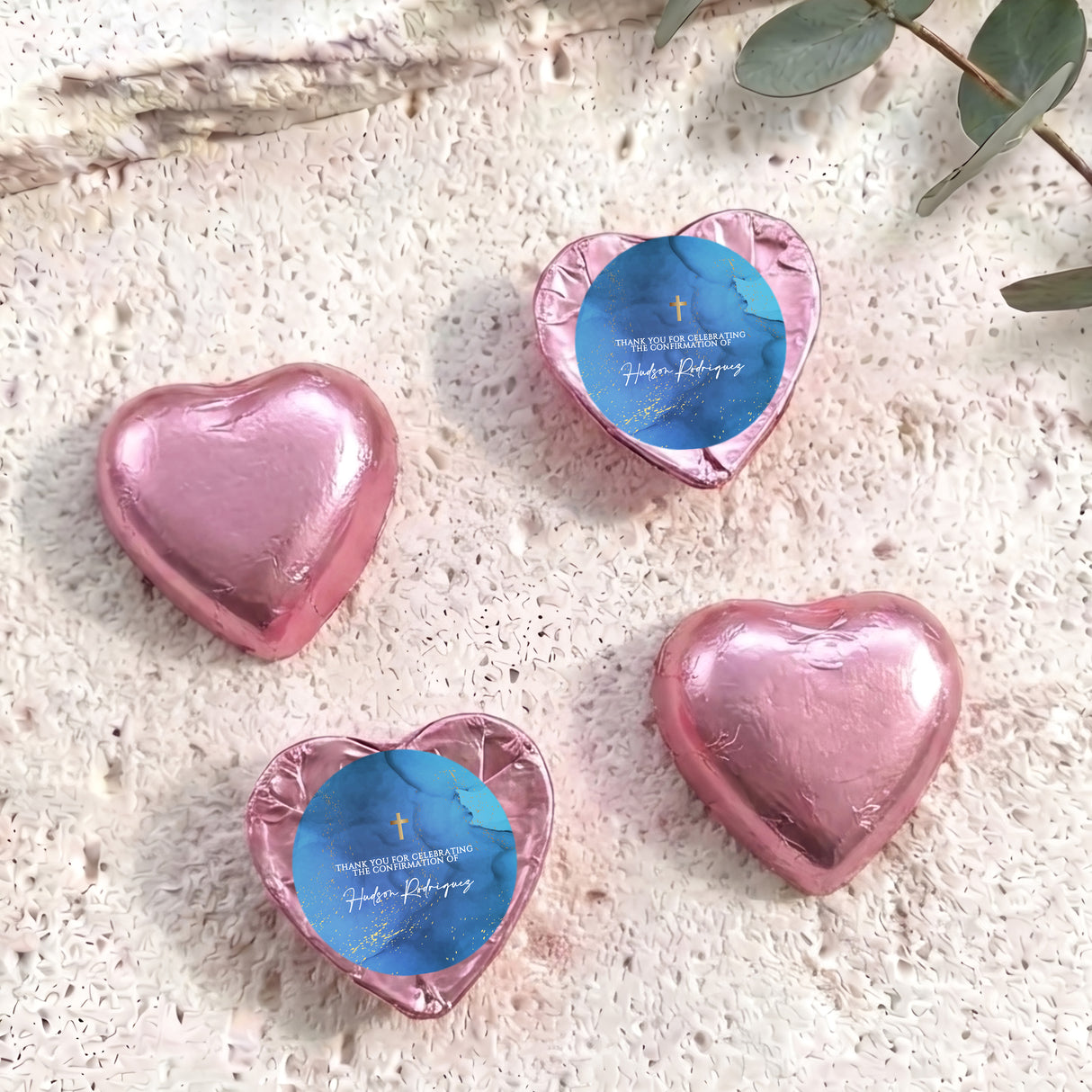 Foil-covered chocolate hearts, pink with blue center labels and gold cross detail