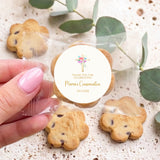 Hand holding cookie with round Marian's Confirmation label, floral holy cross, 30.11.2028