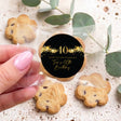 Hand holding bite-size cookie with black & gold 40th birthday star sticker