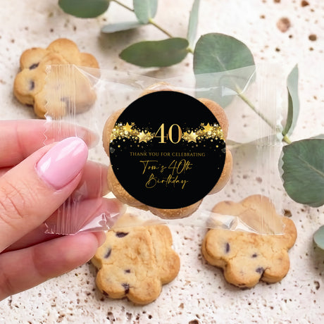 Hand holding bite-size cookie with black & gold 40th birthday star sticker