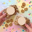 Personalised pretzel bags with clear plastic packaging and beige labels, filled with pretzels.