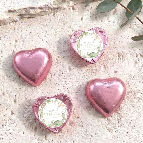 Pink foil-covered chocolate hearts with “Tyler is three” dinosaur-themed birthday label.