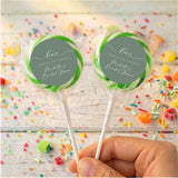 Personalised wrapped lollipops with round sage-green labels and green ribbon accents on sticks
