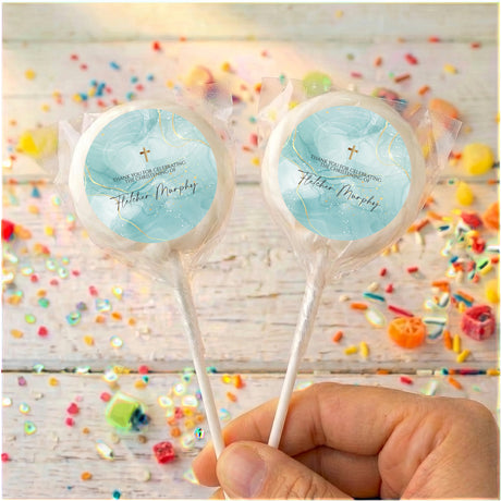 Light blue christening lollipops with gold cross and printed names on round wrappers