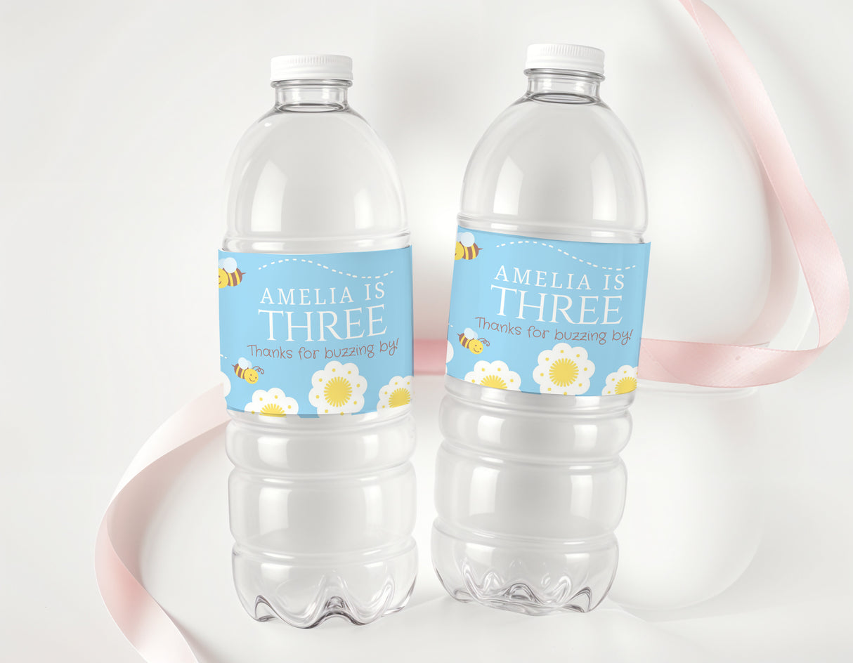 Personalised water bottle labels on clear bottles, blue strip reading AMELIA IS THREE