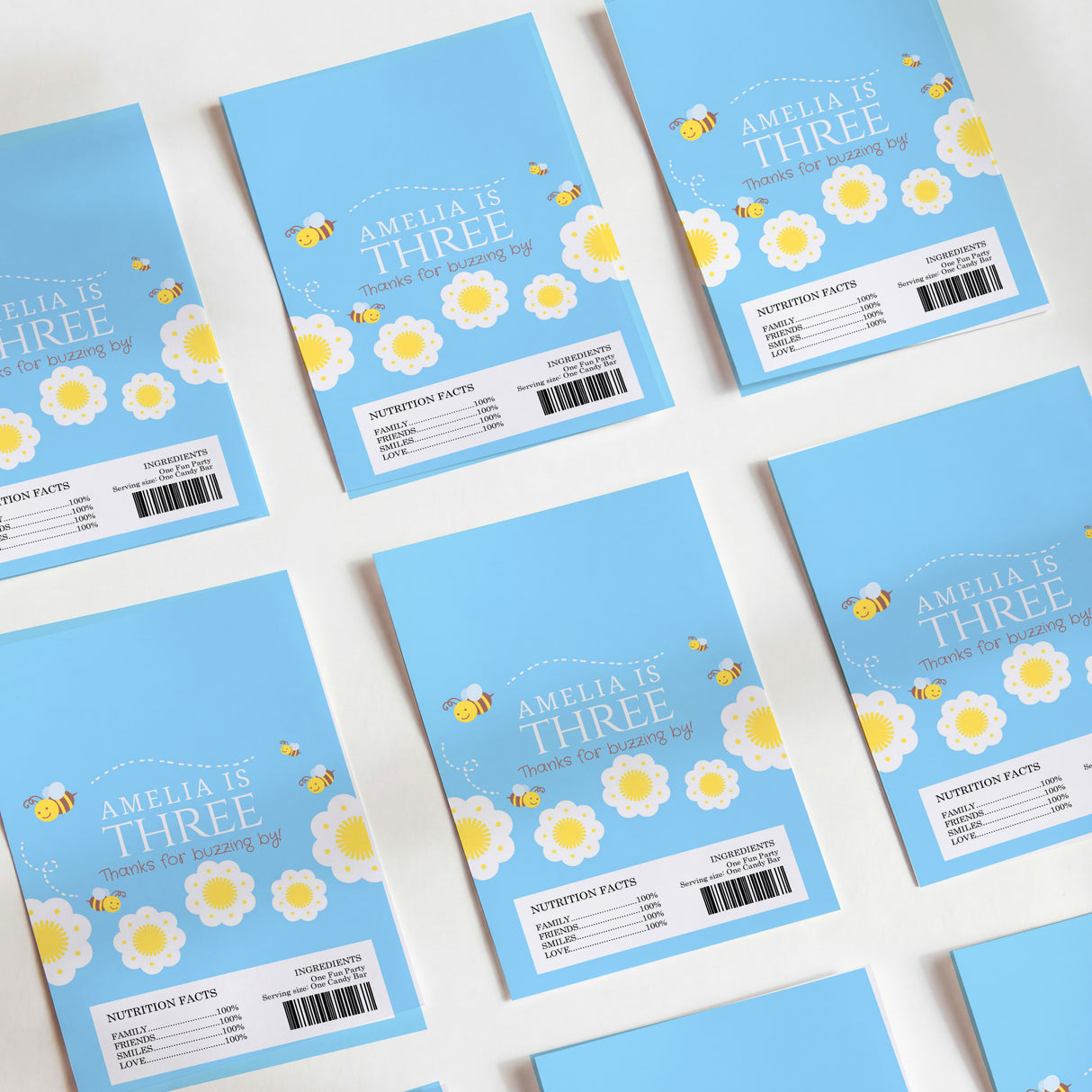 Blue DIY chocolate wrappers with bee flowers and “Amelia is Three”