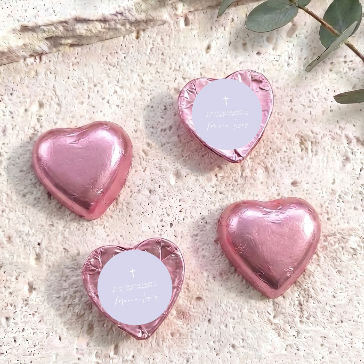 Pink foil-covered chocolate hearts with white center card, cross and name text