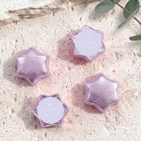 Lilac/purple foil-covered chocolate stars with a white round label and cross