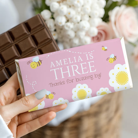Pink bee-themed birthday chocolate bar wrapper with Amelia’s Three text and bee graphics