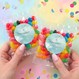 Two confirmation jelly bean bags with blue labels and gold cross, held in hands, assorted candies