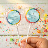 Blue cross lollipops with multicolor rim on clear sticks, held in hand
