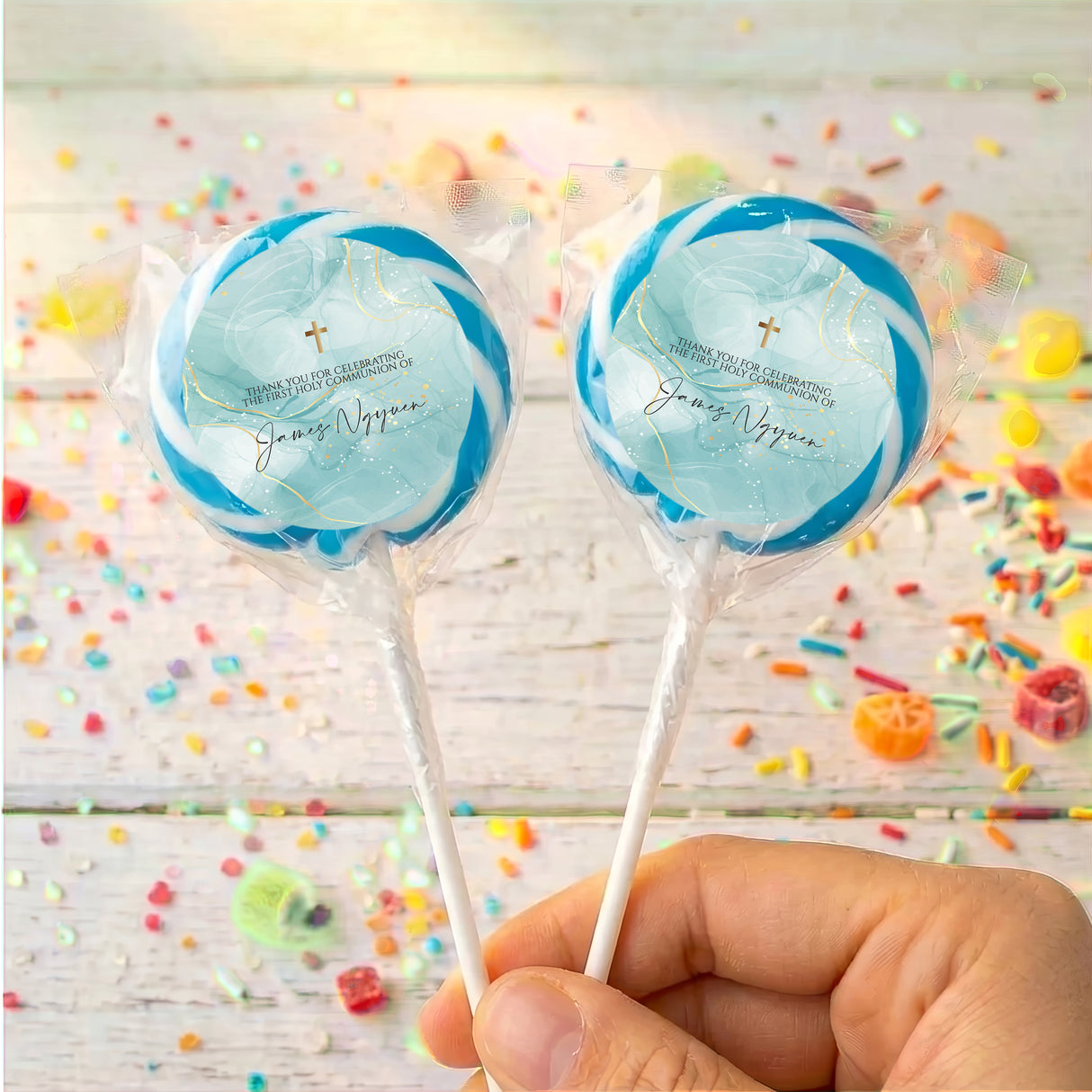 Two blue cross lollipops in clear wrappers on sticks, held in hand
