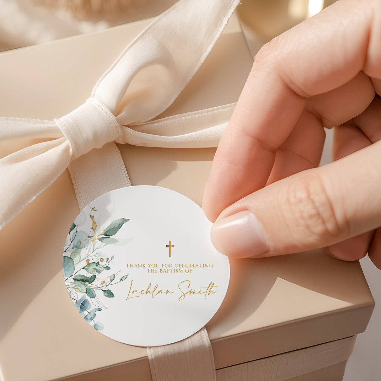 Round baptism favor label with green leaves, gold cross, and Thank you text