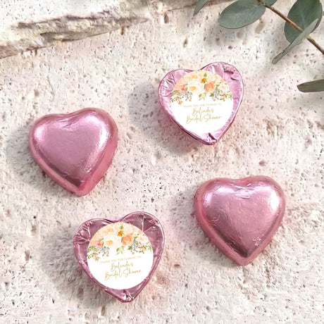 Foil heart chocolates with floral label, four pink heart sweets arranged.