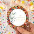 Baptism thank-you sticker with gold cross and green leaves, inside sprinkle-filled bag