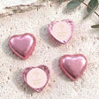 Pink foil-covered chocolate hearts with cross logo on white label