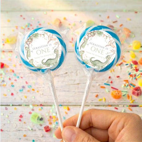 Personalised first birthday dinosaur lollipop with blue ring, clear wrapper, two on sticks