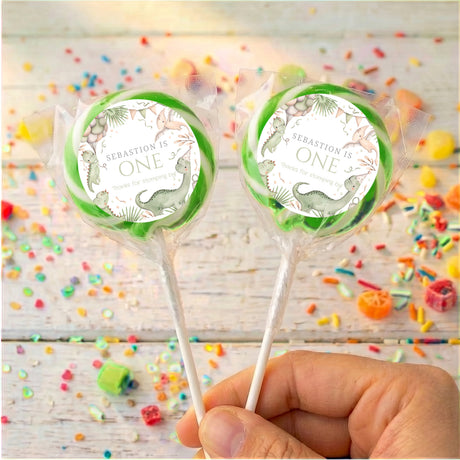 Personalised first birthday dinosaur lollipop with green ring, clear wrapper, two on sticks