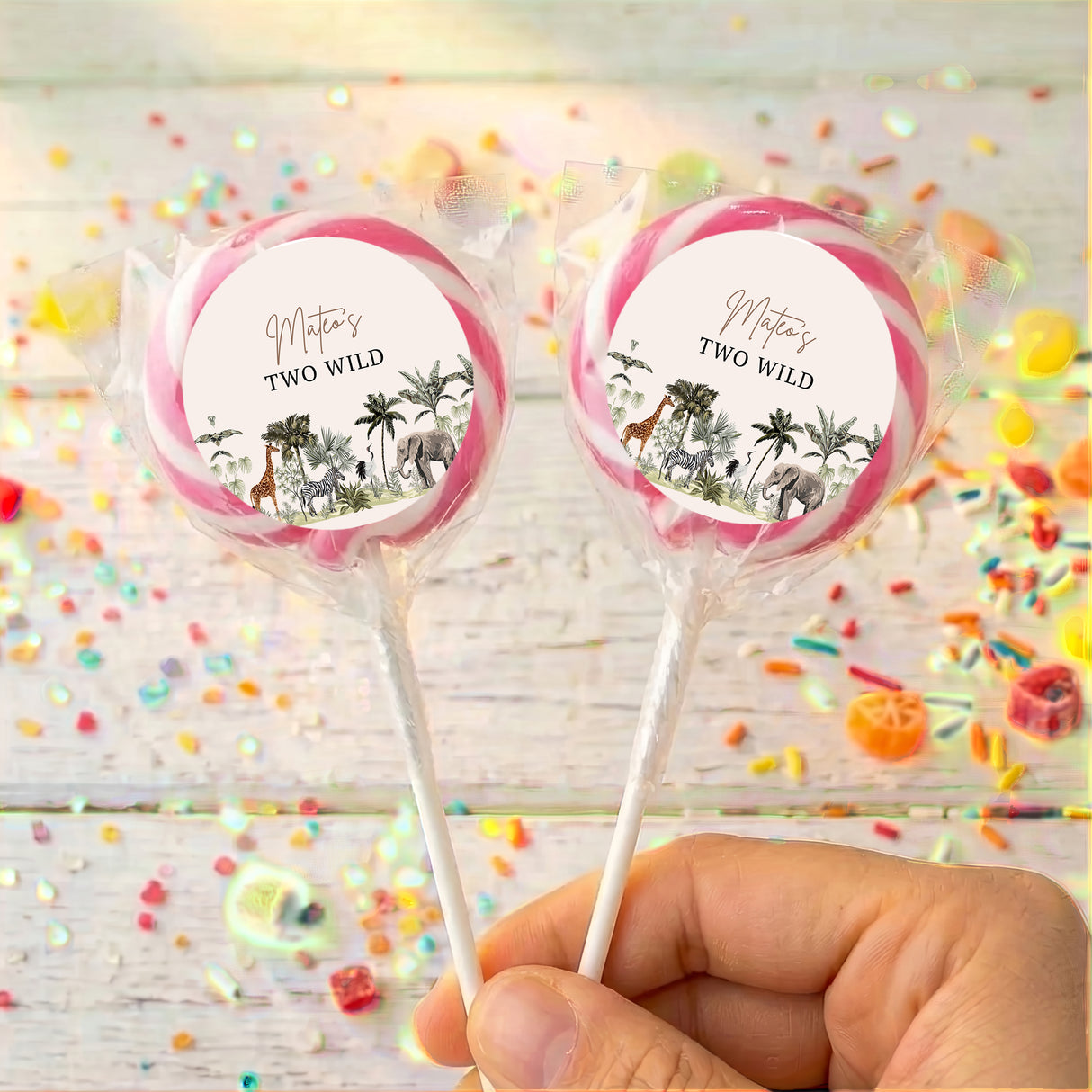 Personalized lollipops with jungle labels and pink rims, held in hand