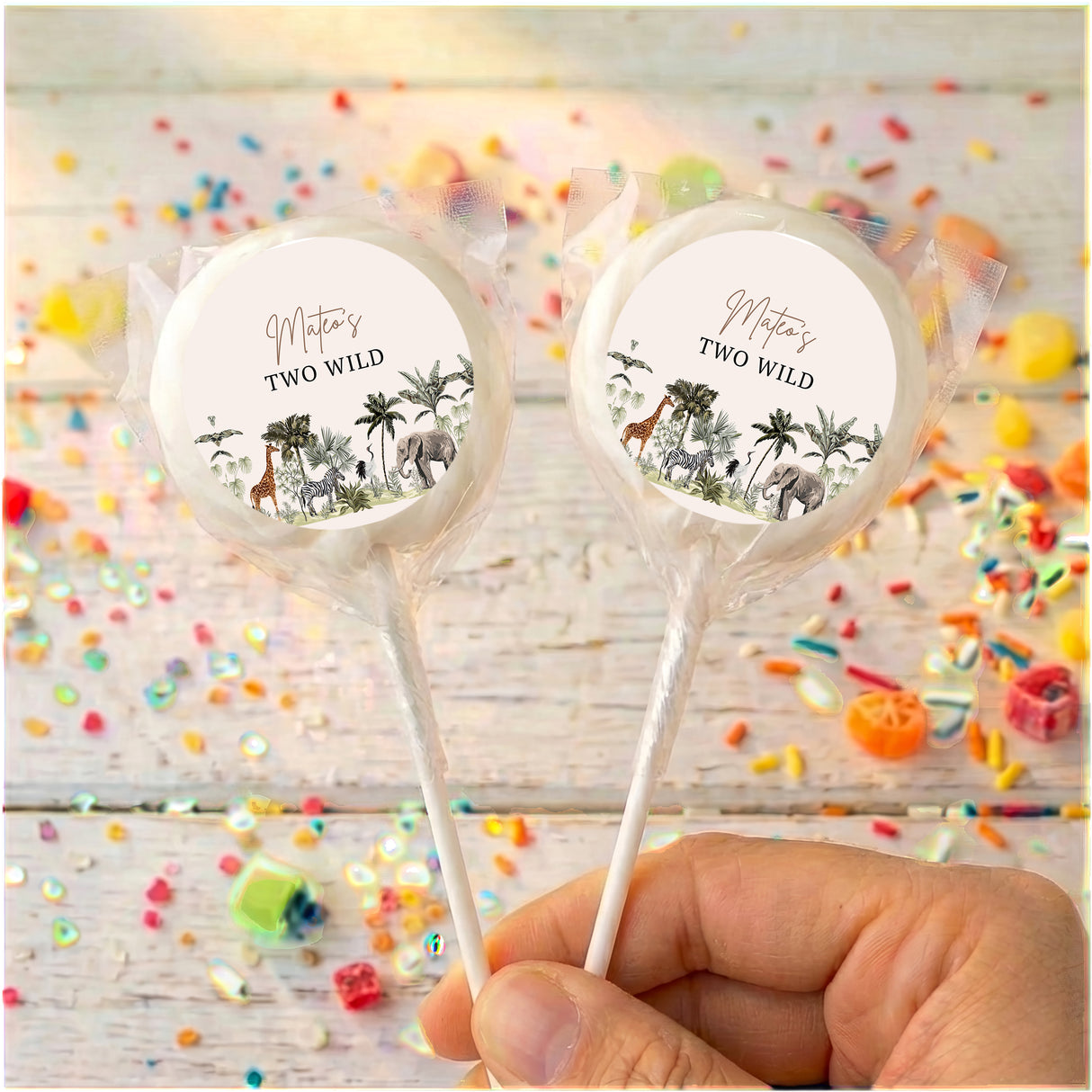 Personalized lollipops with jungle labels and clear wrappers, held in hand