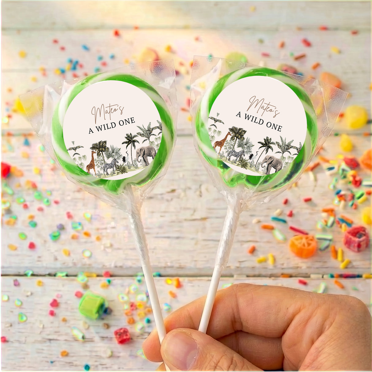 Personalised jungle-themed lollipops with green border, round label reading 'A wild one'.