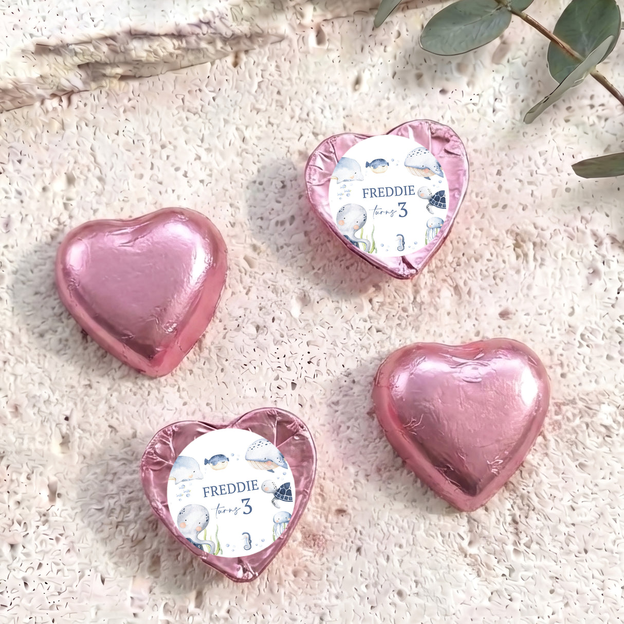 Personalised foil-covered pink chocolate hearts with name Freddie on a white label