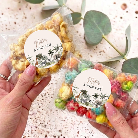 Personalized jungle popcorn bag with round label and colorful popcorn, held by hand
