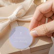 Round lilac cross confirmation label with printed text, attached with white ribbon