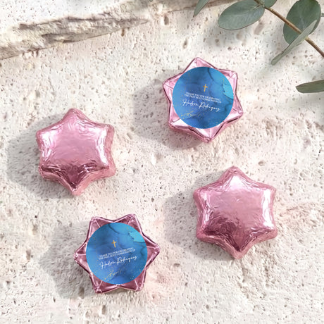 Pink foil chocolate stars with blue personalised circle label and gold cross