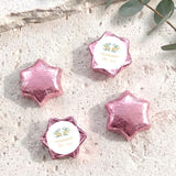 Pink foil-covered chocolate stars with personalised circular cross label on the foil wrapper