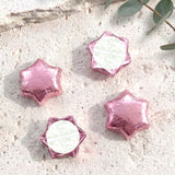 Pink foil-covered chocolate stars with white center labels, arranged in a cluster.