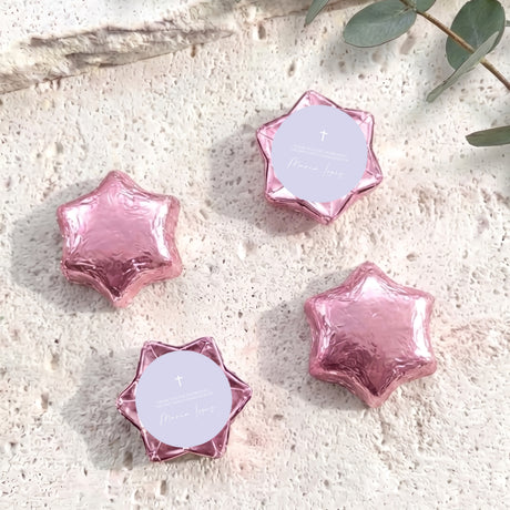 Pink foil-covered chocolate stars with white round labels and a small cross