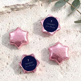 Foil-covered chocolate stars set with pink center label and white cross print